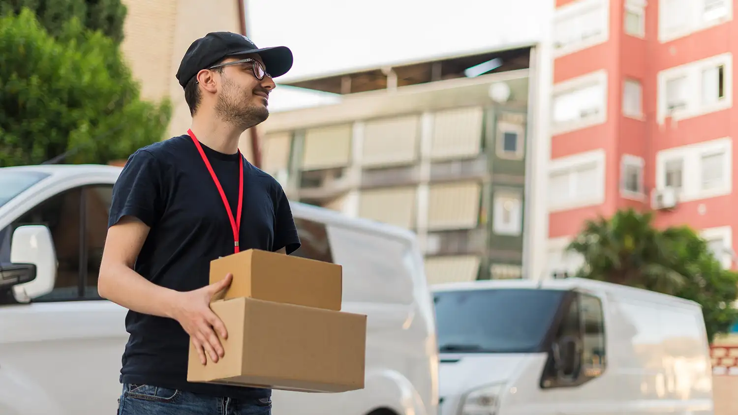 Zusteller in der Stadt mit einem glücklichen Gesichtsausdruck, der ein Paket ausliefert, mit dem Lieferwagen im Hintergrund.